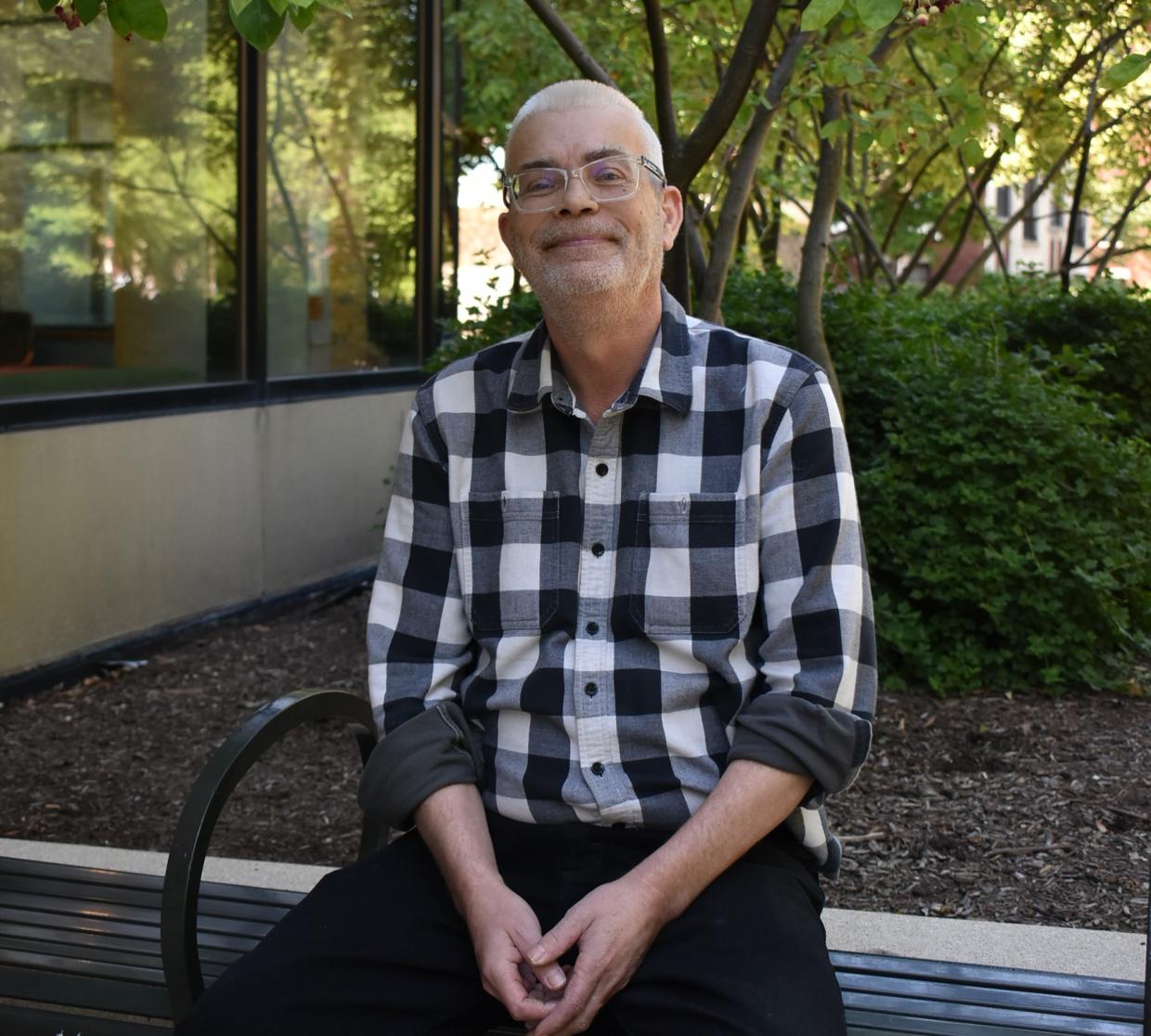 Craig O sits outside on a park bench