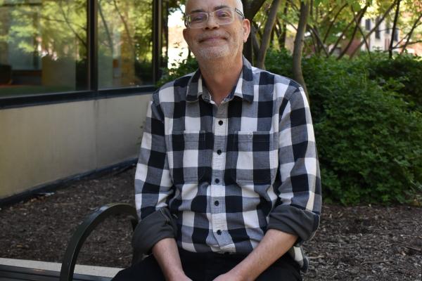 Craig O sits outside on a park bench